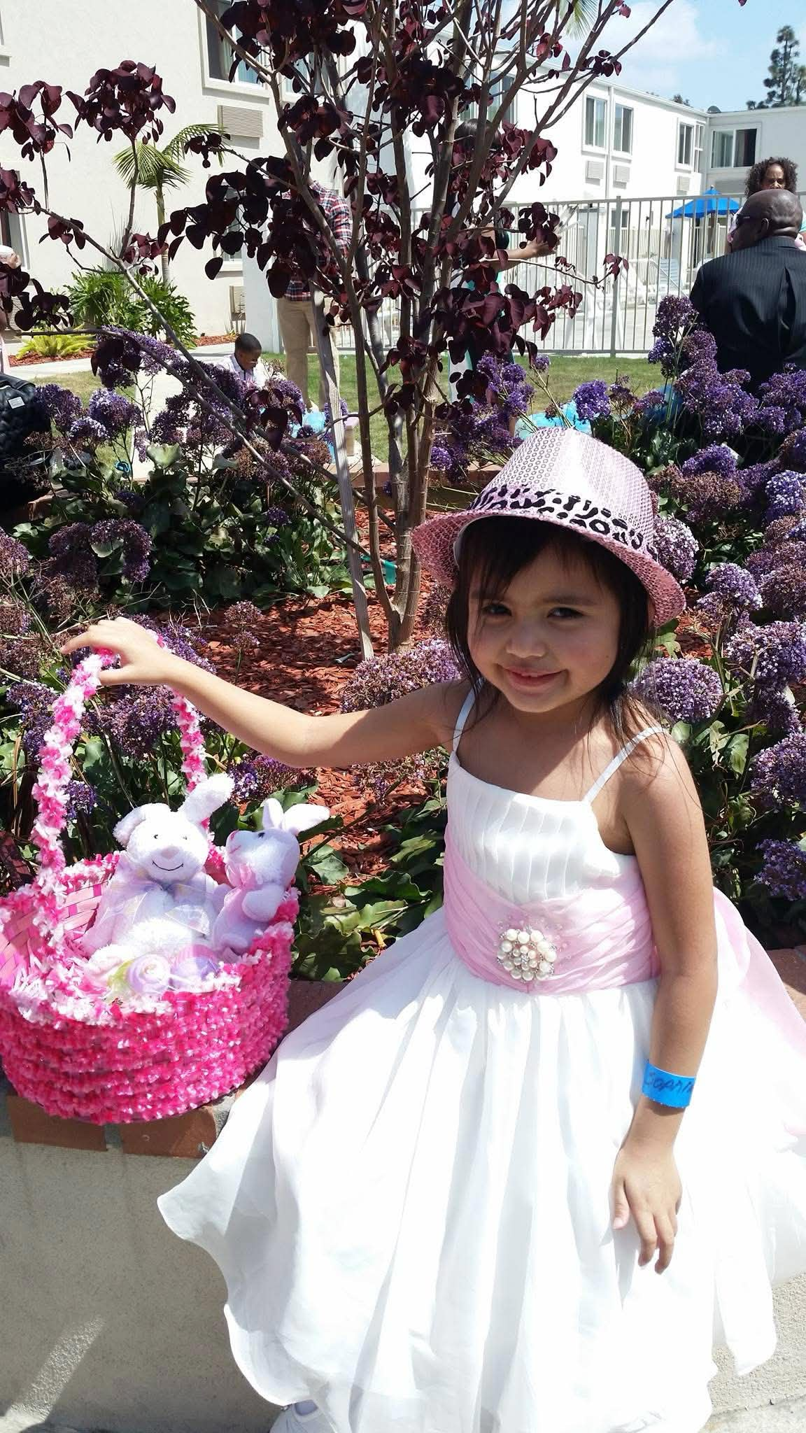 young Scarlette in a white dress and pink hat holding an Easter basket